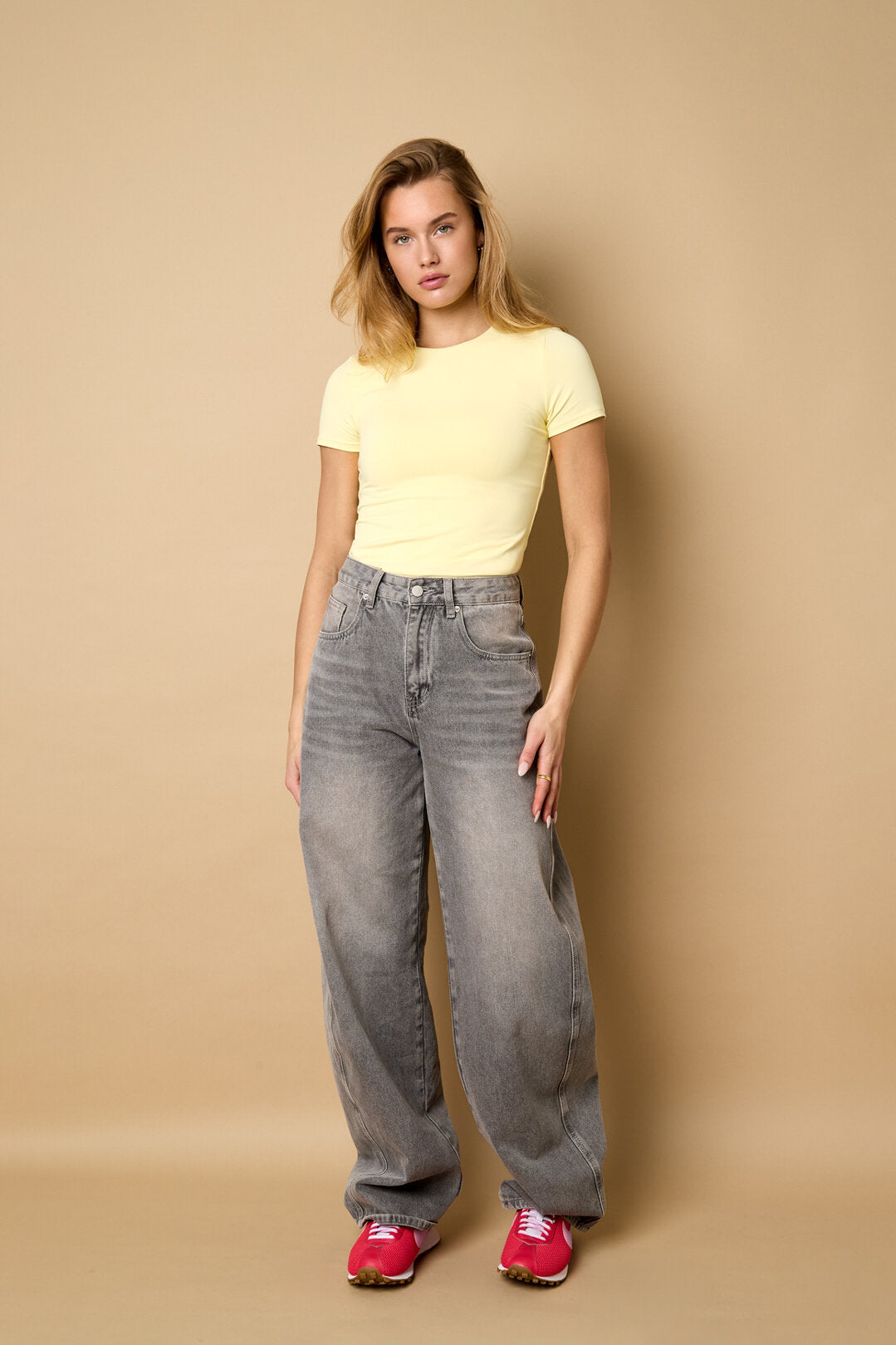 Zachtgeel basic T-shirt in vol beeld, op een grijze wide-leg jeans